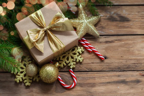 Decoraciones navideñas. Regalo envuelto artesanalmente con ramas de abeto y decoración navideña sobre fondo de madera . — Foto de Stock