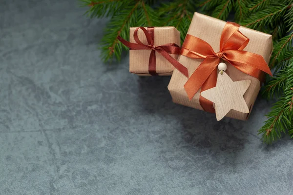 Karácsonyi dekoráció. Két ajándék csomagolt kézműves fenyő ágak sötét szürke háttér. — Stock Fotó