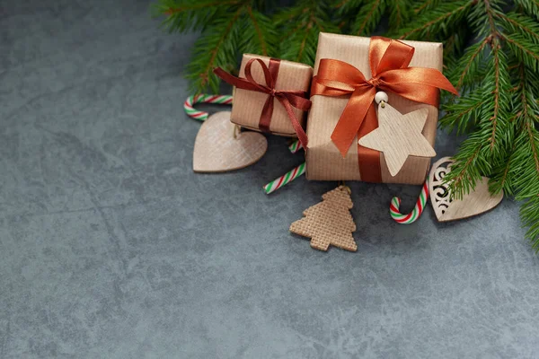 Рождественские украшения. Два подарка завернутые ремесло с еловыми ветвями и праздничное украшение на темно-сером фоне . — стоковое фото