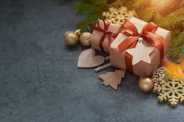 Weihnachtsdekoration. zwei Geschenke verpackt Handwerk mit Tannenzweigen und Feiertagsdekoration auf dunkelgrauem Hintergrund. — Stockfoto