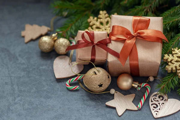 Vánoční ozdoby. Dva dárky zabalené řemeslo s jedlovými větvemi a prázdninové dekorace na tmavě šedém pozadí. — Stock fotografie