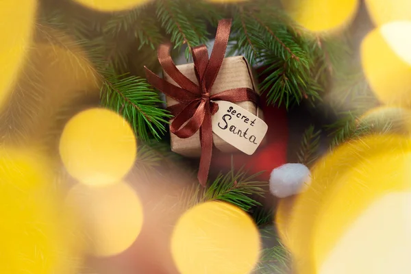 Kerstcadeau of doos met tag geheim santa met Santa hoed op donkere achtergrond. — Stockfoto