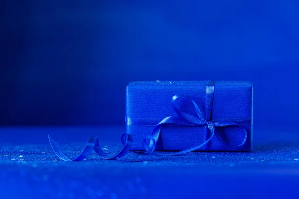 Синя подарункова коробка з синім бантом на темно-синьому фоні. Святкова концепція . — стокове фото