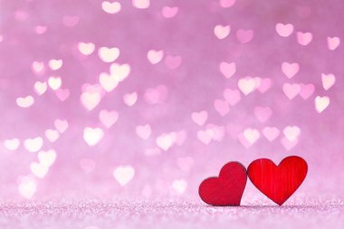 Sevgililer Günü tebrik kartı. İki kırmızı ahşap kalp pembe arka planda aşk kavramında şekillenir.