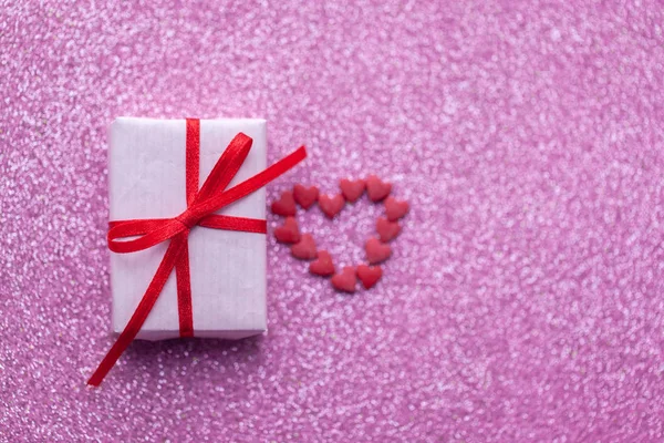 Geschenkdoos met rode en witte hartjes op roze glitter achtergrond valentijnsdag concept. — Stockfoto