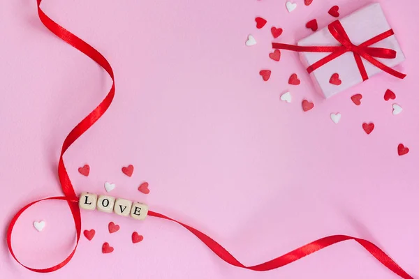Ημέρα του Αγίου Βαλεντίνου έννοια λέξη "αγάπη" με λευκό και κόκκινο καρδιές και κουτί δώρου σε παστέλ ροζ φόντο. Επίπεδο lay, πάνω όψη, αντιγραφή χώρου — Φωτογραφία Αρχείου
