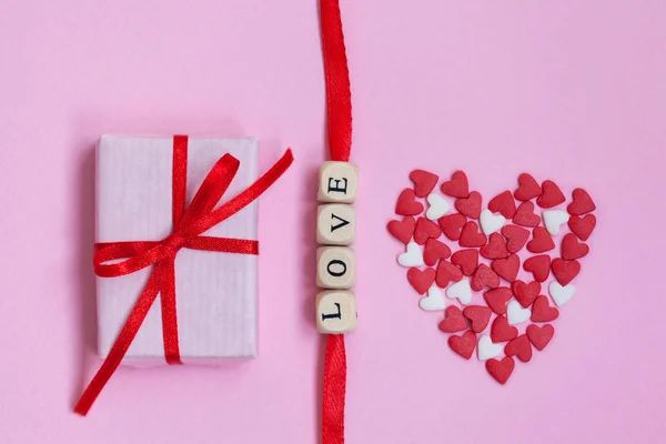 バレンタインデーの単語"愛"パステルピンクの背景に白と赤の心とギフトボックスと。バレンタインデーのコンセプト。フラットレイアウト、トップビュー、コピースペース — ストック写真