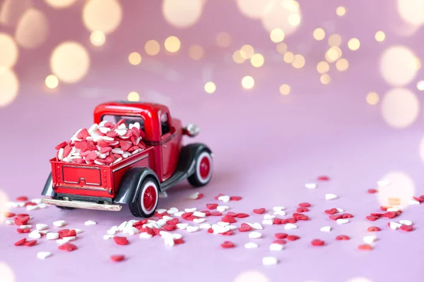 Игрушечный красный автомобиль с подарочной коробкой на крыше на розовом фоне. День святого Валентина фон . — стоковое фото