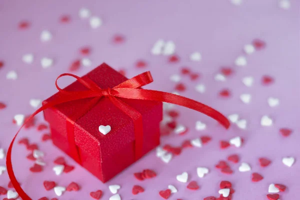 Rode geschenkdoos en confetti hartjes op roze achtergrond. Valentijnsdag concept. — Stockfoto