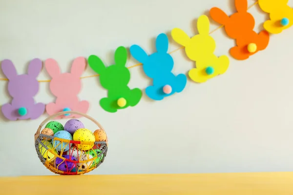 色彩艳丽的鸡蛋在篮子里 背景是手工制作的兔子复活节花环 概念东东 — 图库照片