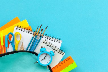 Okula dönüş kavramı. Mavi arka planda malzeme içeren mavi okul çantası. FLat yatıyordu.