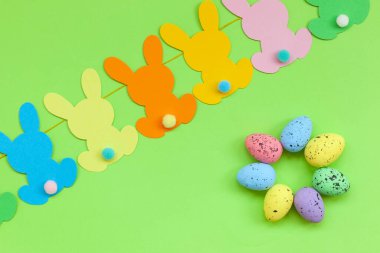 Renkli Paskalya yumurtaları ve yeşil arka planda el yapımı paskalya çelengi. Üst manzara, düz yatış. Mutlu Paskalyalar.