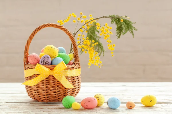 色彩艳丽的复活节彩蛋在一个白色木制背景的篮子里 上面点缀着一丛丛的油菜花 春假概念 — 图库照片