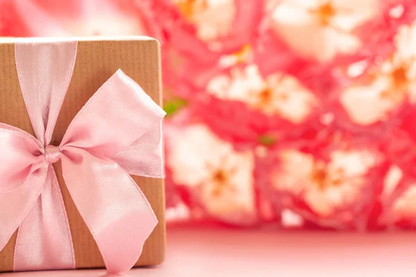 Подарункова Коробка Загорнута Ремісничим Папером Рожевим Бантом Фоні Рожевих Квітів — стокове фото