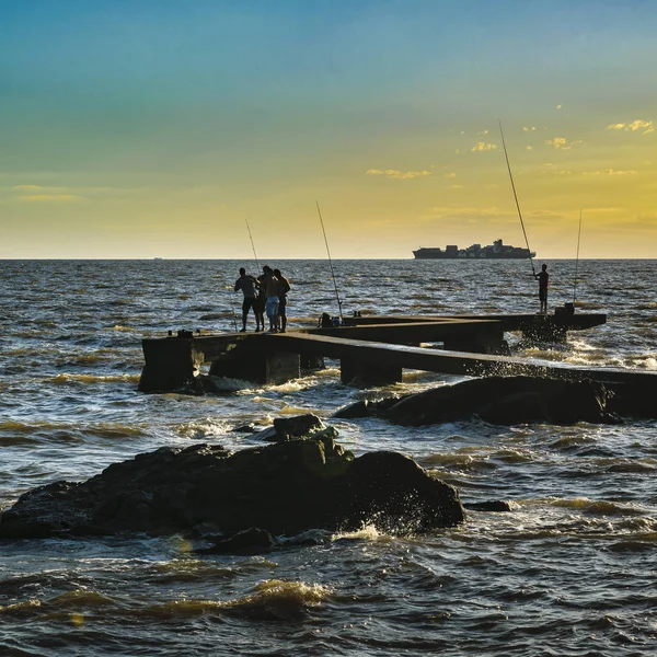 Mensen vissen op de golfbreker van rivier — Stockfoto