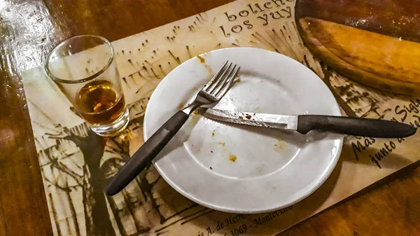 "Брудний обід і скляний кубок" з Лікеуром через дерев'яний стіл — стокове фото