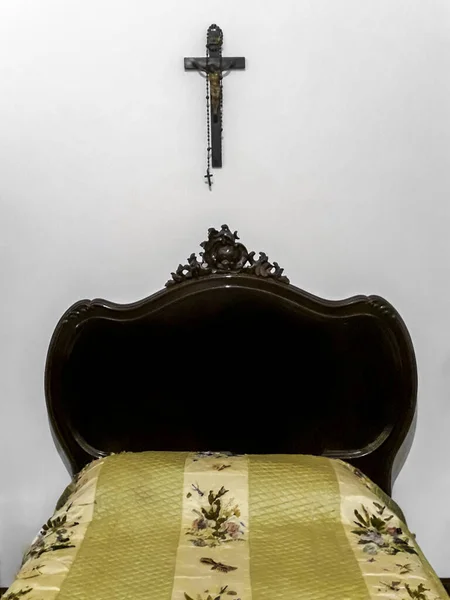壁に掛けられた小さなベッドと十字架付きのレトロな19世紀のスタイルの寝室のインテリアシーン — ストック写真