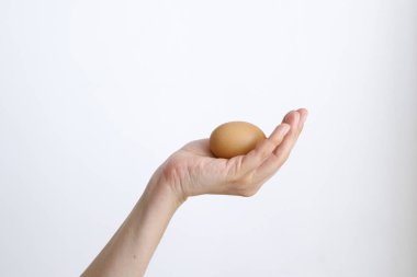 Gündüz vakti beyaz bir arka planda tavuk yumurtası olan bir kadın.