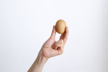 Gündüz vakti beyaz bir arka planda tavuk yumurtası olan bir kadın.