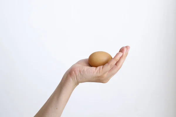 Gündüz vakti beyaz bir arka planda tavuk yumurtası olan bir kadın.