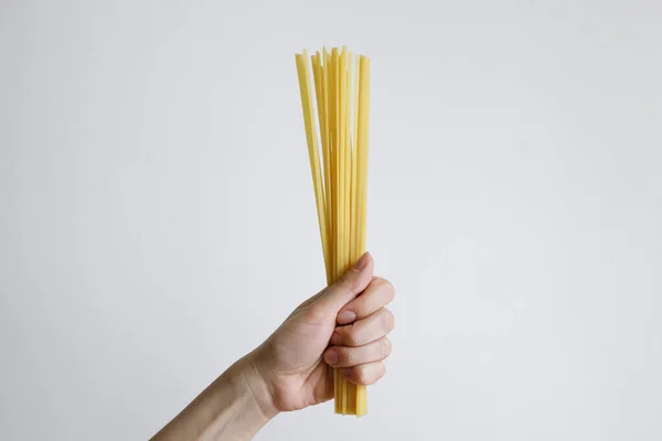 Beyaz bir arka planda gün ışığında çiğ spagetti yiyen bir kadın.