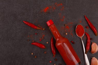 Siyah arka planda bir şişe acı sos.