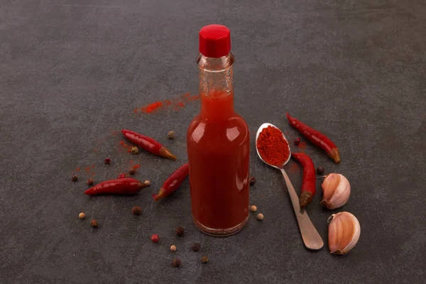 Bottle of spicy red hot sauce on black background