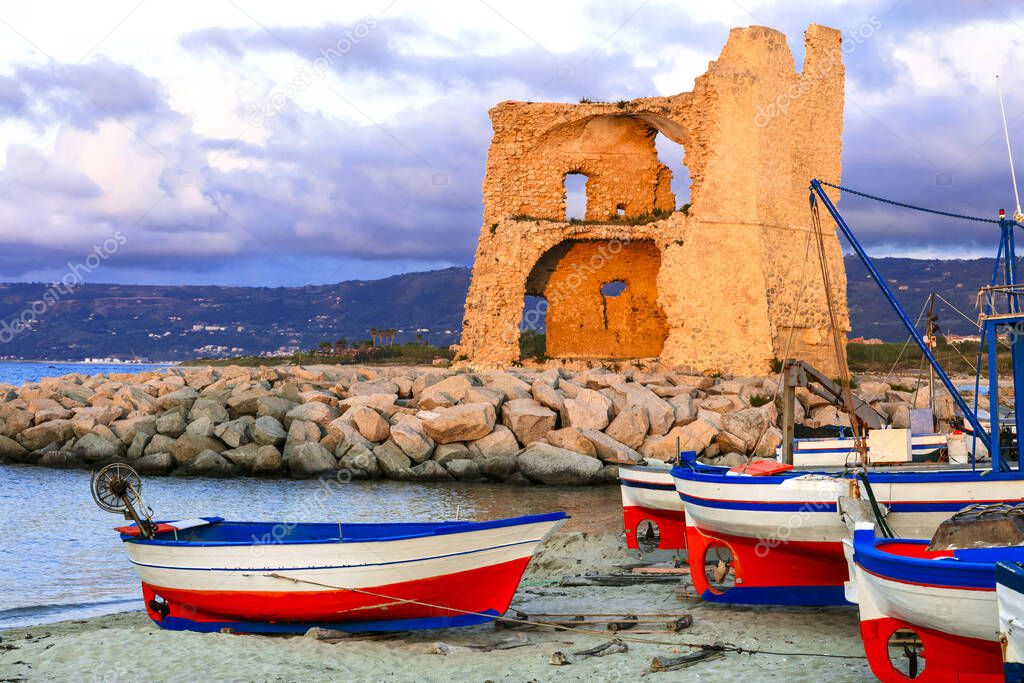  Calabria, Italy. Picturesque old harbour with tradtional fishing boat over sunset.