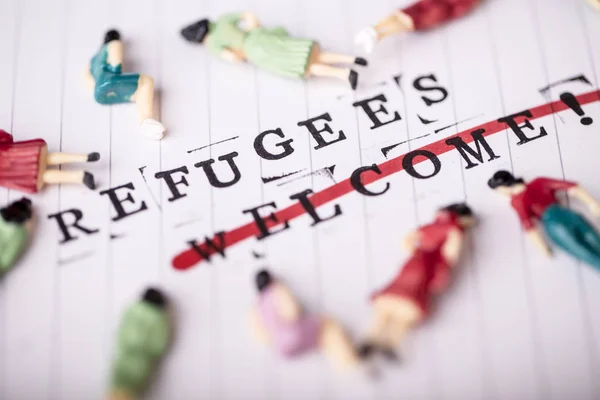 Flüchtlinge begrüßen durchgreifenden Text auf Papier — Stockfoto