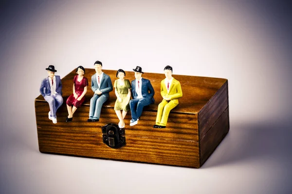 Toy models of people sitting on the wooden box — Stock Photo, Image