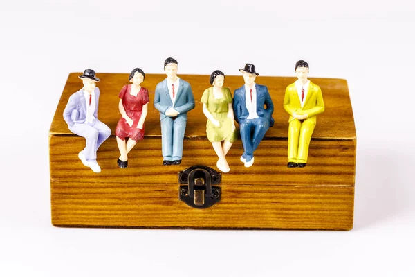 Toy models of people sitting on the wooden box — Stock Photo, Image