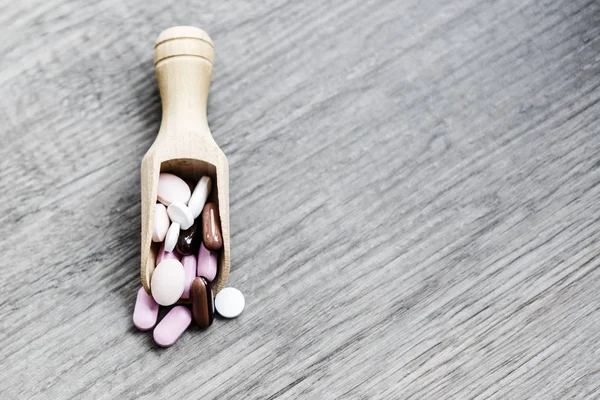 Pílulas na colher no chão de madeira — Fotografia de Stock