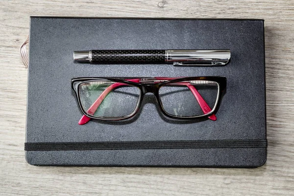 Calendar or diary with pen and glasses on wooden table,  floor — Stock Photo, Image