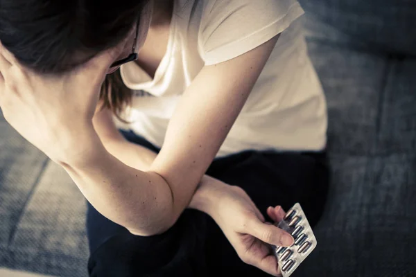 Mujer joven con dolor de cabeza y pastillas — Foto de Stock