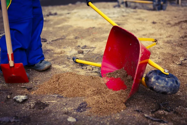 Child play with sand, red shovel and small cute barrow — Stock Photo, Image