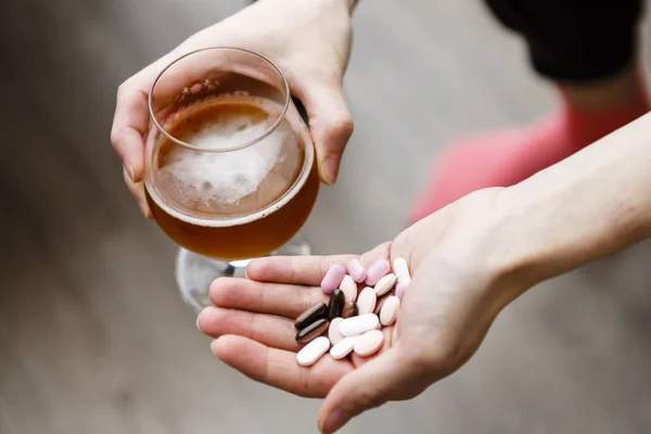 Problème de dépendance, femme avec des pilules et de la bière dans les mains . — Photo