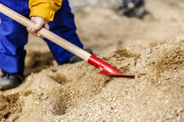 Criança brincar com areia e pá vermelha — Fotografia de Stock