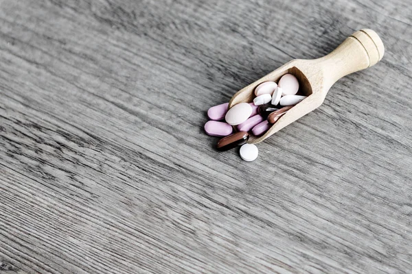 Pílulas na colher no chão de madeira — Fotografia de Stock