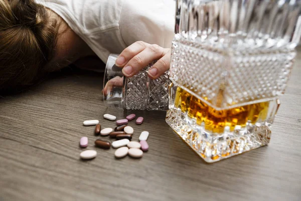 Drunk or poisoned young woman with bottle of alcohol and pills Stock Picture