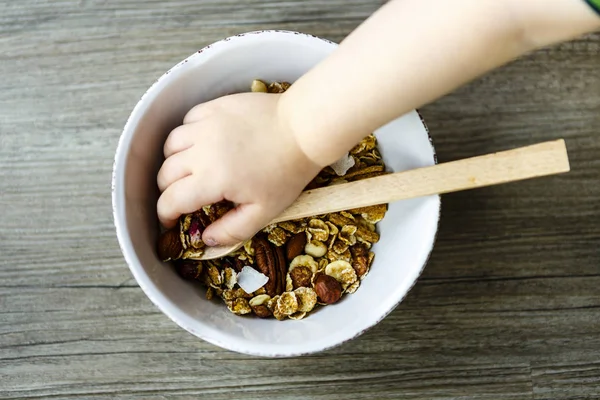 Skål med müsli och sked på trä bordet förberett för hälsosam frukost, barn hand — Stockfoto