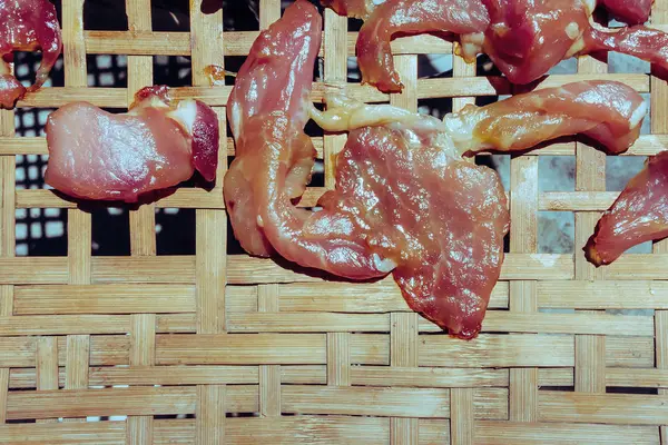 Close up to pork cut put on bamboo weaving and dry by the sun for cooking. Traditional thai food has a name called Sun-dried pork.