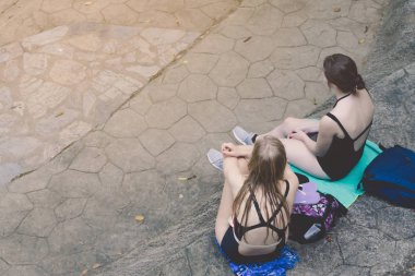 Siyah mayo kadın turistlerin üst görünümü oturup Kanchanaburi, Tayland Erawan şelale oynadıktan sonra yol kenarında dinlenmek.