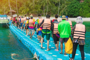 Plastik duba üzerinde yürüyen bir grup turist sahile gider..