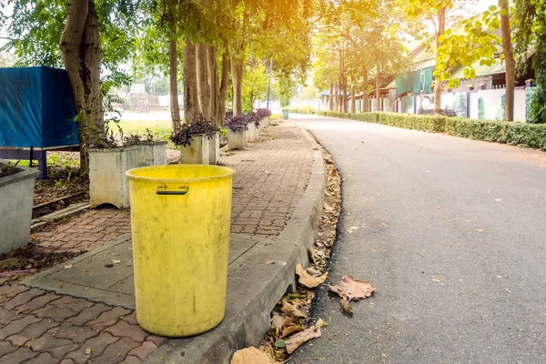 Un viejo cubo de basura amarillo en el parque público al lado del camino a pie para proteger el medio ambiente . — Foto de Stock