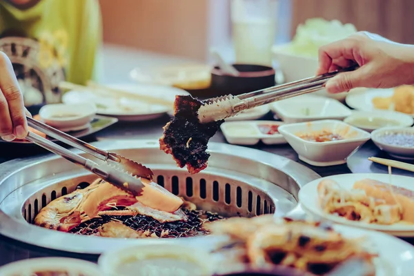 Menschen grillen Fleisch auf einem rauchlosen Grill in einem Restaurant. — Stockfoto