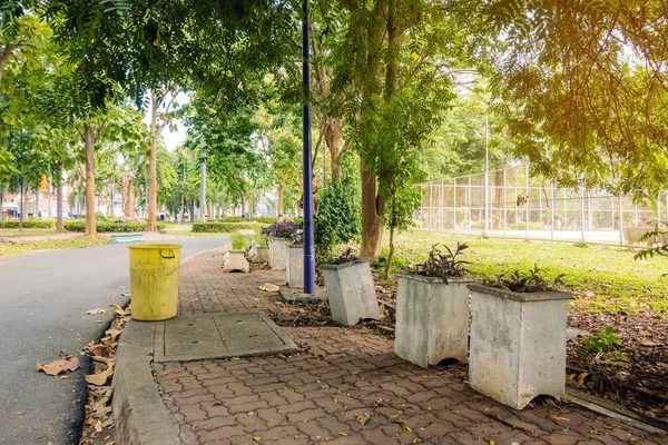 Un viejo cubo de basura amarillo en el parque público al lado del camino a pie para proteger el medio ambiente . — Foto de Stock