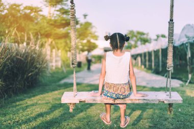Salıncakta sallanan genç kızın arkası görünüyor. Annesini organik üzüm çiftliğinde bekliyor..