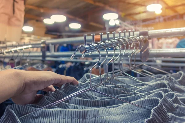 People check and choose pants to buy on hangers in a clothing store.