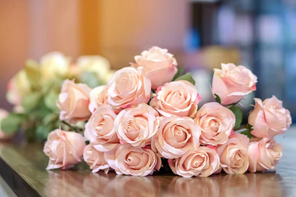 Krásná kytice růžových umělých růží na stole zdobí kavárnu. — Stock fotografie