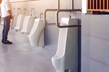 Engelli ya da paslanmaz çelik saplı yaşlı insanlar için dost tasarımı olan temiz ve modern kamu erkekler tuvaleti ve benzin istasyonunda otomatik sensör sifonlu beyaz seramik sidik torbaları. Paslanmaz çelik kulplara odaklan.